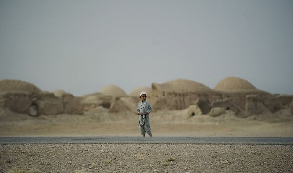 Афганский мальчик из племени Паштун смотрит, как соединенный патруль солдат 1-го взвода 1-64 танкового батальона армии США, находящийся под командованием НАТО, проходит через деревню Морган-Кеча в провинции Кандагар, 8 сентября 2012 года. (Тони Карумба / AFP Photo / Getty Images)