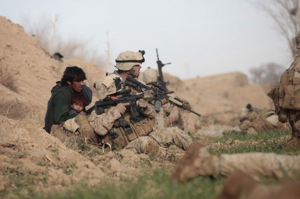 Американские солдаты морской пехоты и з компании Браво, 6-ая морская пехота - младший капрал Крис Сандерсон (сзади) и сержант Тревис Доусон (спереди) защищают афганского мужчину с ребенком от боевиков Талибана, открывших огонь в городе Марджа, провинции Гельманд, 13 февраля 2010 года. Войска НАТО под командованием США пошли в нападение на последнюю большую крепость Талибана в Афганистане, одной из самых горячих провинций, и боевики быстро открыли огонь. (Рейтер / Горан Томашевич)