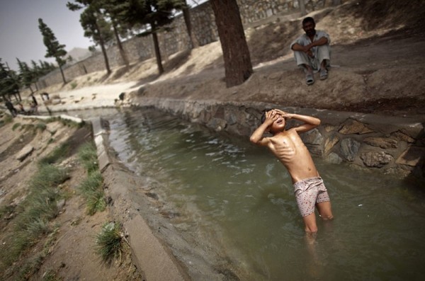 Афганский мальчик закрывает руками глаза и падает назад спиной в ручей в Кабуле, 10 августа 2011 года. (Рейтер / Ахмад Масуд)